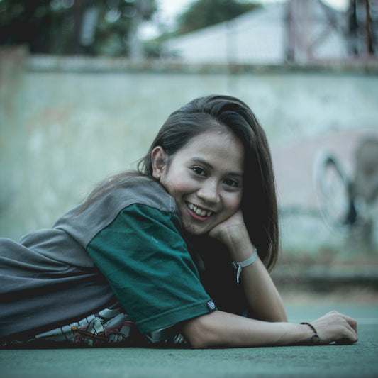 woman wearing grey and green top laying down on pavement