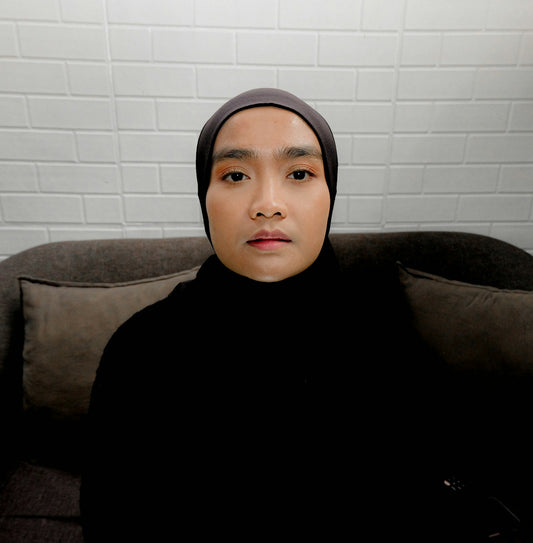 A person wearing a dark hijab and black top